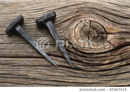 two forged nails on a wooden background 85667425