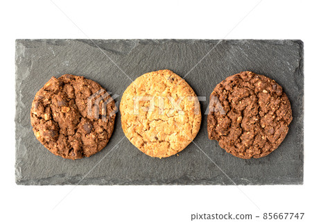 Top view of different varieties of granola cookies on a stone board for serving. Top view of different varieties of granola cookies on a stone board for serving. 85667747