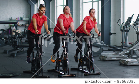 Group of girls performs aerobic training workout cardio routine on bike simulators, cycle training 85668383