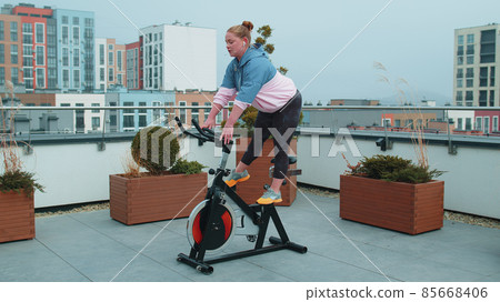 Woman performs aerobic endurance training workout cardio routine on the simulators, cycle training Woman performs aerobic endurance training workout cardio routine on the simulators, cycle training 85668406