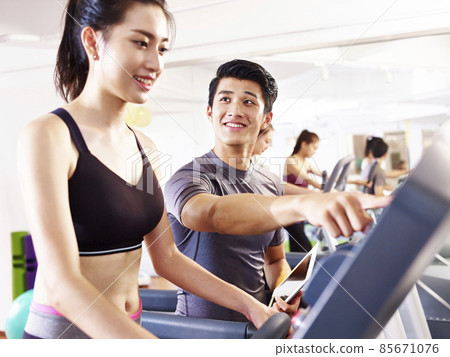 young asian woman running on treadmill coached by young trainer 85671076