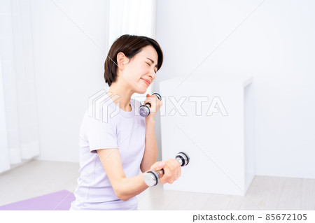 Middle-aged woman doing muscle training with dumbbells 85672105