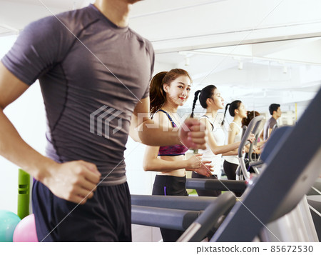 young asian adult running on treadmill, focus on the girl in the middle 85672530