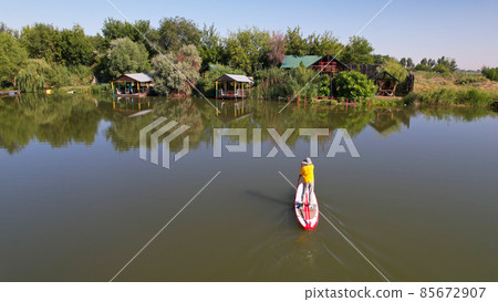 The guy on the sup board is floating on the lake. The guy on the sup board is floating on the lake. 85672907