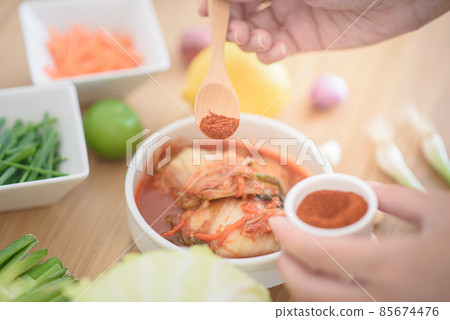 The chef is seasoning kimchi with red chili powder. The chef is seasoning kimchi with red chili powder. 85674476