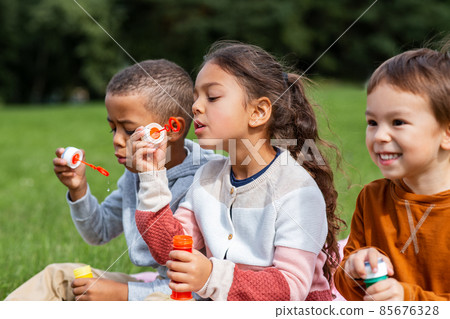 group of children blowing soap bubbles at park group of children blowing soap bubbles at park 85676328