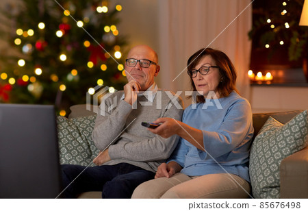 senior couple watching tv at home on christmas 85676498
