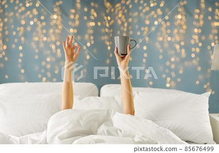 woman with cup of coffee lying in bed showing ok woman with cup of coffee lying in bed showing ok 85676499