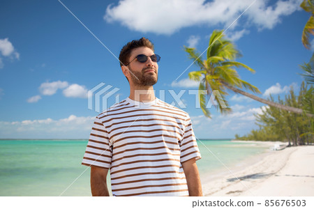 young man in sunglasses on tropical beach 85676503