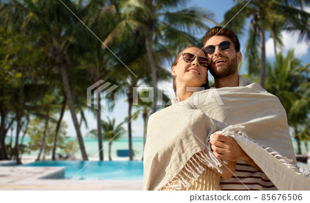 happy couple covered with blanket hugging on beach happy couple covered with blanket hugging on beach 85676506