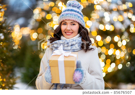 happy woman with christmas gift over lights 85676507