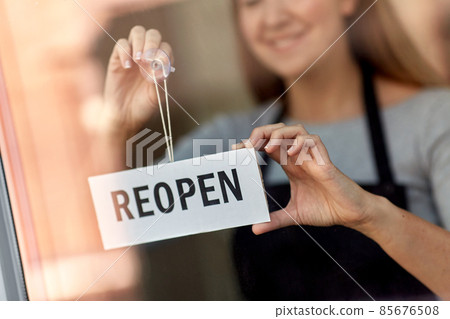 happy woman hanging reopen banner on door glass happy woman hanging reopen banner on door glass 85676508