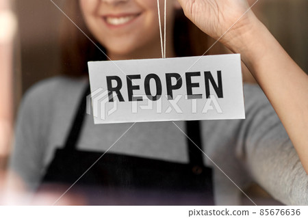 happy woman hanging reopen banner on door glass happy woman hanging reopen banner on door glass 85676636