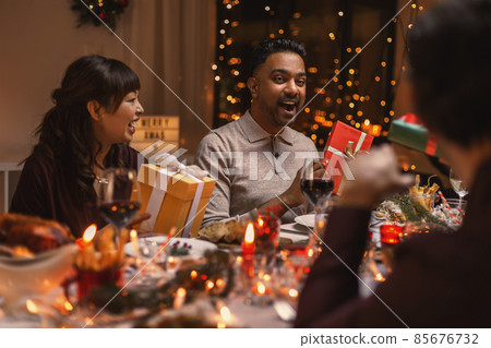 happy friends opening christmas presents at home 85676732