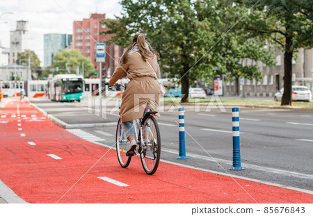 woman riding bicycle along red bike lane in city 85676843
