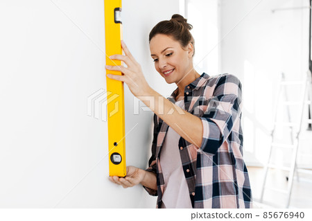 happy woman with level measuring wall at home happy woman with level measuring wall at home 85676940