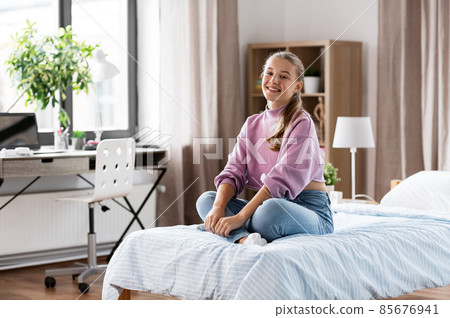 happy smiling girl sitting on bed at home happy smiling girl sitting on bed at home 85676941