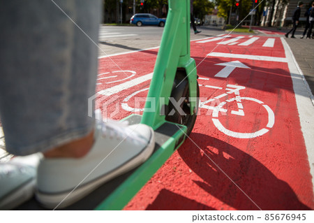 woman riding scooter along bike lane road in city woman riding scooter along bike lane road in city 85676945
