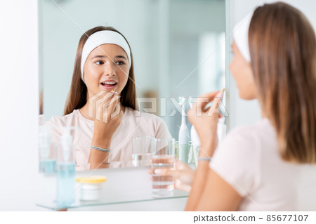teenage girl taking cod liver oil at mirror teenage girl taking cod liver oil at mirror 85677107