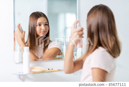 teenage girl using hair styling spray at bathroom teenage girl using hair styling spray at bathroom 85677111