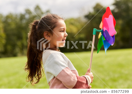 happy little girl with pinwheel playing at park 85677299