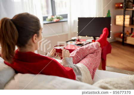woman watching tv and drinking coffee on christmas 85677370