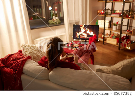 woman watching tv and drinking coffee on christmas 85677392