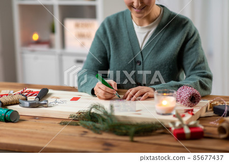 woman with stencil and marker drawing on christmas woman with stencil and marker drawing on christmas 85677437
