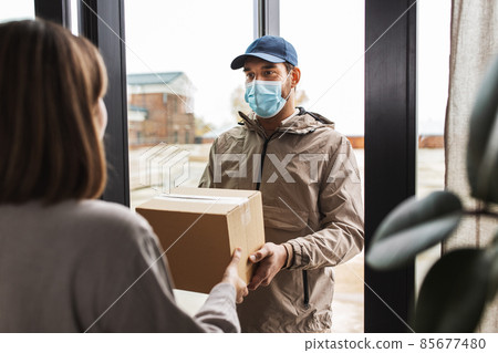 delivery man in mask giving parcel to customer delivery man in mask giving parcel to customer 85677480