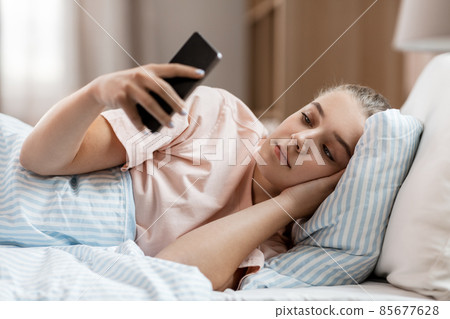 girl with smartphone in bed at home girl with smartphone in bed at home 85677628