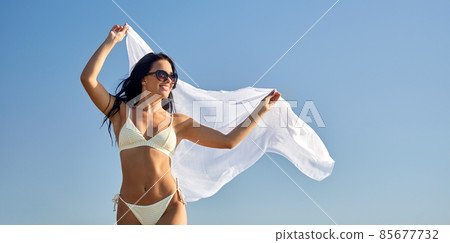 woman in bikini swimsuit with cover-up over sky woman in bikini swimsuit with cover-up over sky 85677732