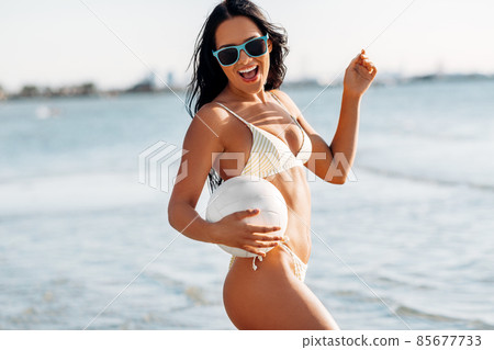 woman in bikini posing with volleyball on beach woman in bikini posing with volleyball on beach 85677733