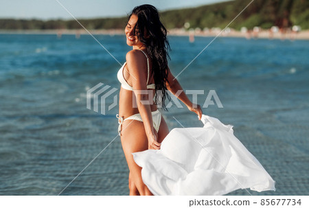 woman in bikini swimsuit with cover-up on beach woman in bikini swimsuit with cover-up on beach 85677734