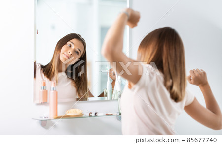 teenage girl looking in mirror at bathroom teenage girl looking in mirror at bathroom 85677740