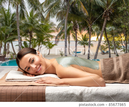 woman with clay mask on back at spa over beach woman with clay mask on back at spa over beach 85677865
