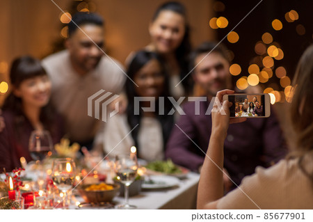 happy friends photographing at christmas dinner happy friends photographing at christmas dinner 85677901