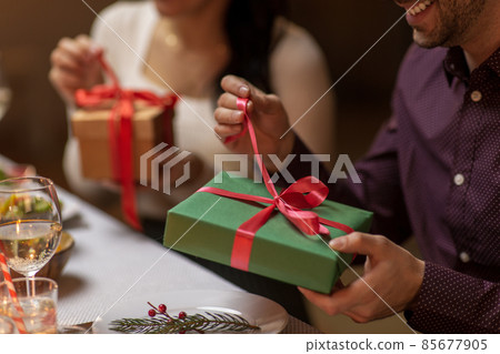 happy people with christmas gifts at dinner party happy people with christmas gifts at dinner party 85677905
