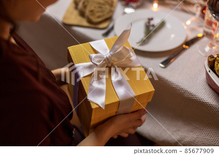happy woman opening christmas gift at dinner party happy woman opening christmas gift at dinner party 85677909