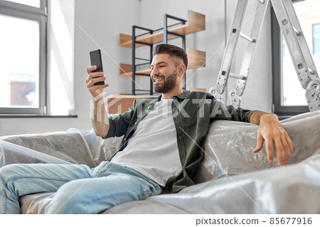 smiling man with smartphone moving into new home smiling man with smartphone moving into new home 85677916