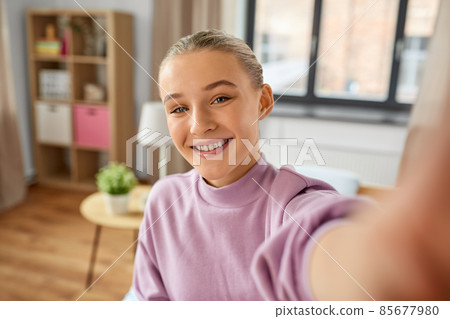 happy smiling girl taking selfie at home 85677980