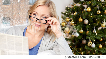 woman in glasses reading newspaper on christmas woman in glasses reading newspaper on christmas 85678018