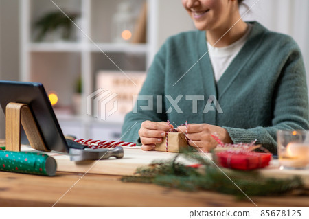 happy woman with tablet pc packing christmas gift happy woman with tablet pc packing christmas gift 85678125