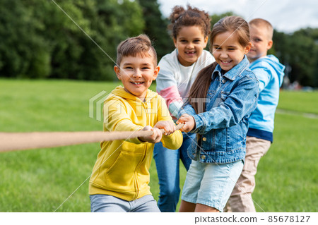 happy children playing tug-of-war game at park happy children playing tug-of-war game at park 85678127