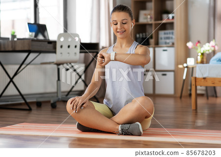 teenage girl with gadgets exercising at home teenage girl with gadgets exercising at home 85678203