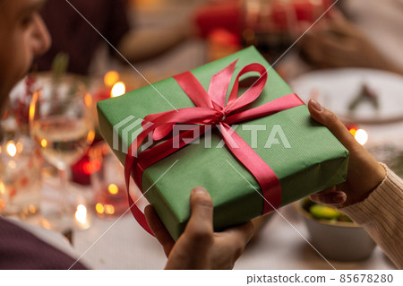 hands holding christmas gift at dinner party hands holding christmas gift at dinner party 85678280
