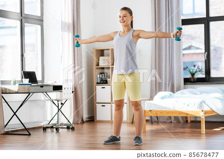 teenage girl with dumbbells exercising at home 85678477