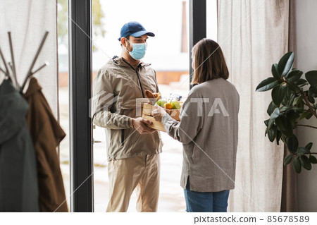 food delivery man in mask giving order to customer food delivery man in mask giving order to customer 85678589