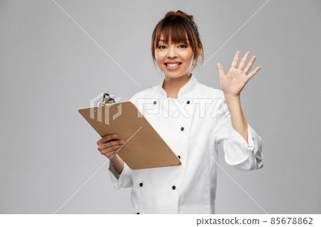 smiling female chef with clipboard waving hand smiling female chef with clipboard waving hand 85678862