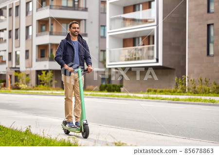 happy smiling man riding electric scooter in city happy smiling man riding electric scooter in city 85678863