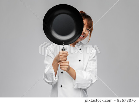 female chef peeking out from behind frying pan female chef peeking out from behind frying pan 85678870